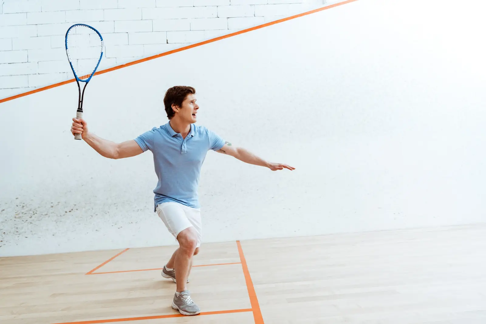 Squashspieler im weißen Court beim Rückhandschlag